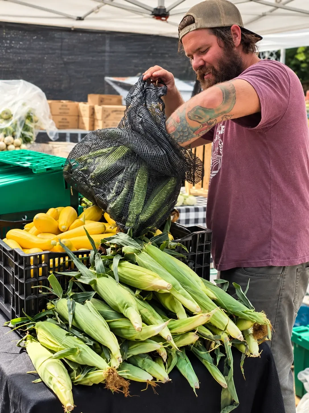 A grower handling fresh corn at the farm stand
